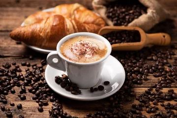 Foto op Plexiglas Keuken Een kopje cappuccino met koffieboon als achtergrond.