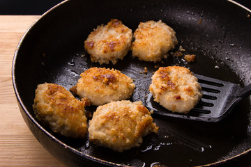 Fried chicken cutlets with a crispy crust in oil, in a pan. Delicious junk food.