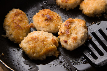 Fried chicken cutlets with a crispy crust in oil, in a pan, close-up. Delicious junk food.
