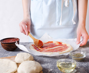 Obraz na płótnie Canvas Chef applying tomato sauce on the pizza dough top.Preparation of classic italian pizza