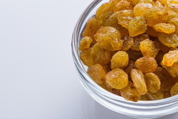 golden raisins on a white acrylic background