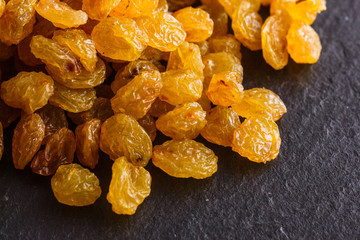 golden raisins on a dark stone background