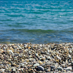 Sea pebble - gravel beach in sunlight, selective focus for background.
