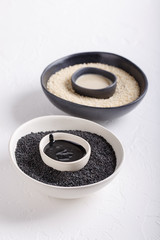 Black tahini and white tahini sauce in bowls on white background. Natural paste made from sesame seeds. Copy space.