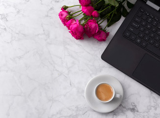 Feminine workspace with laptop computer, bouquet of roses and coffee on a marble table. 