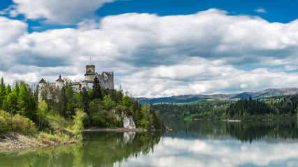 Fototapeta na wymiar Panoramic view at Niedzica castle over Czorsztyn lake in polish Pieniny mountains. Smooth lake water and clouds at blue sky