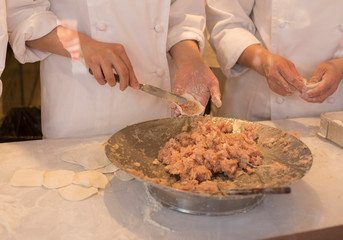 Hands of chefs stuffing meat for the grilled rice dumplings at Chinatown in Kobe in Japan