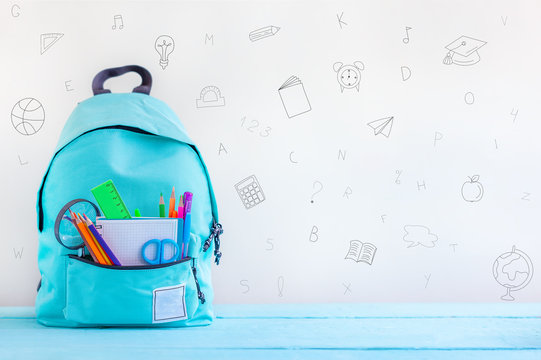 Concept back to school. Full turquoise School Backpack with stationery on table.