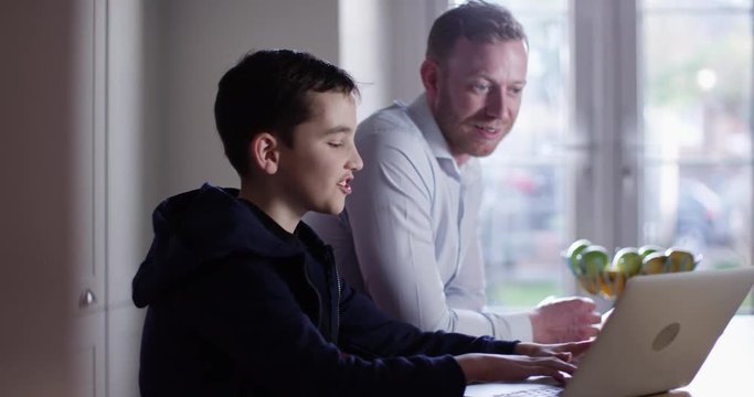 4K Happy father & son spending time together, chatting & laughing while surfing the web. Slow motion.
