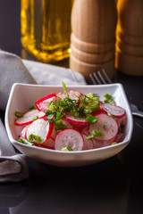 Radish salad in a white bowl on a dark background
