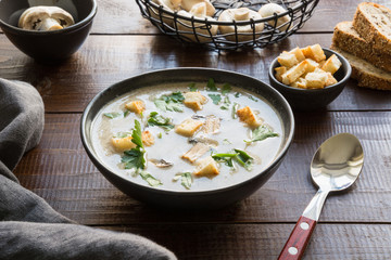 Mushroom champignon cream soup on dark wooden board. Close up.
