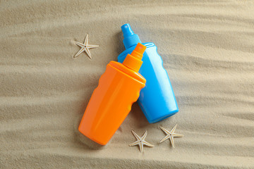 Fototapeta na wymiar Clear sea sand with starfish and sunscreens, space for text. Summer vacation background