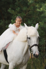 Fototapeta premium happy little princess on white horse in the forest