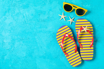 Flip flops, sunglasses and starfishes on color background, space for text and top view. Summer...