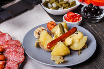 young woman is preparing a traditional Swiss cheese raclette