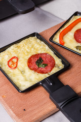 young woman is preparing a traditional Swiss cheese raclette