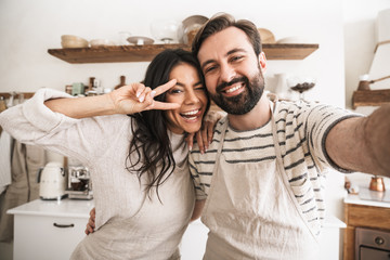 Portrait of positive couple taking selfie photo while cooking in kitchen at home