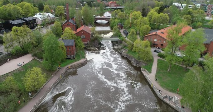 Aerial footage of Vanhankaupunginkoski waterfall on Vantaanjoki River and Power Plant Museum buildings located in Old Helsinki on the Western fork of the Vantaa River.