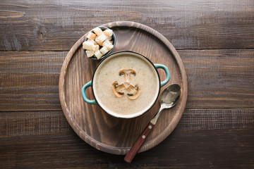 Mushroom champignon cream soup on dark wooden board. View from above.