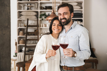 Portrait of young european couple drinking wine from glasses while having romantic dinner at home