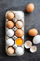 Fresh organic raw eggs, white, beige and brown, one is cracked