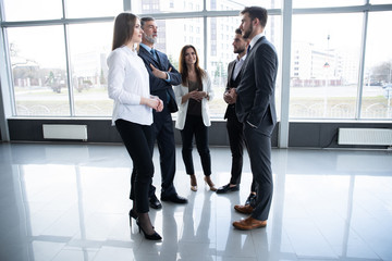 Fototapeta premium Group of Busy Business People Concept. Business team discussing work in office building hallway.