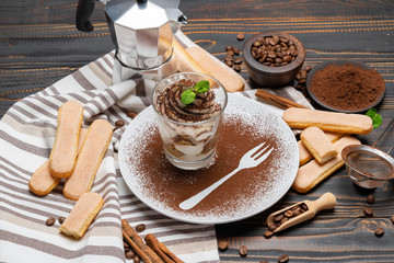 Classic tiramisu dessert in a glass on wooden background