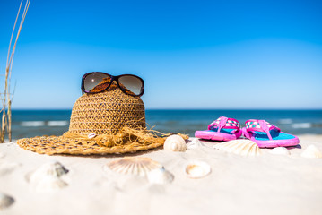 Background with vacation accessories on the beach - sunglasses hat and flip flop on sand. Summer...