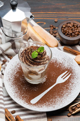 Classic tiramisu dessert in a glass on wooden background