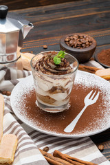Classic tiramisu dessert in a glass on wooden background