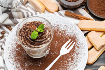 Classic tiramisu dessert in a glass on wooden background