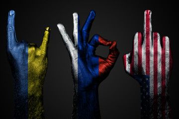 a set of three hands with a painted flag of Ukraine, Russia and USA show middle finger, goat and Okay, a sign of aggression, protest and approval on a dark background. © Алексей Еремеев