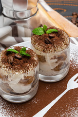 Classic tiramisu dessert in a glass on wooden background