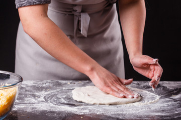 Obraz na płótnie Canvas young woman in a gray aprong prepares a pepperoni pizza