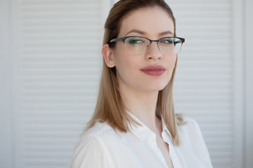 Portrait of a young stylish business woman in a white shirt and glasses.
