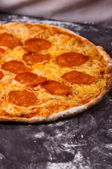 young woman in a gray aprong prepares a pepperoni pizza
