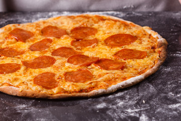 young woman in a gray aprong prepares a pepperoni pizza