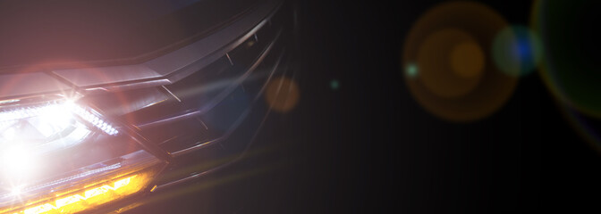 Headlight of a modern car in dense fog against dark background. Exterior details and beauty of technical innovations. Negative space to insert your text or image. Flyer for ad.