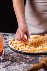young woman in a gray aprons prepares a Hawaiian pizza