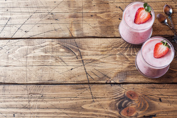Homemade yogurt with fresh strawberries in glasses on a wooden background. Selective focus. Copy space.