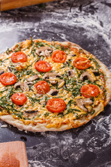 young woman in a gray aprong prepares a vegetarian pizza