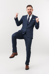 Excited businessman posing isolated over white wall background make winner gesture.