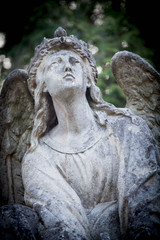 Ancient statue of blind and wounded angel can not fly up. Religious symbols.