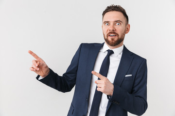 Handsome young businessman posing isolated over white wall background pointing.