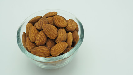 Raw almonds close up in bow and white background.