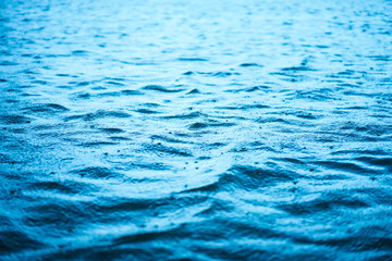 Close up surface of wave blue sea with rain drops abstract background.