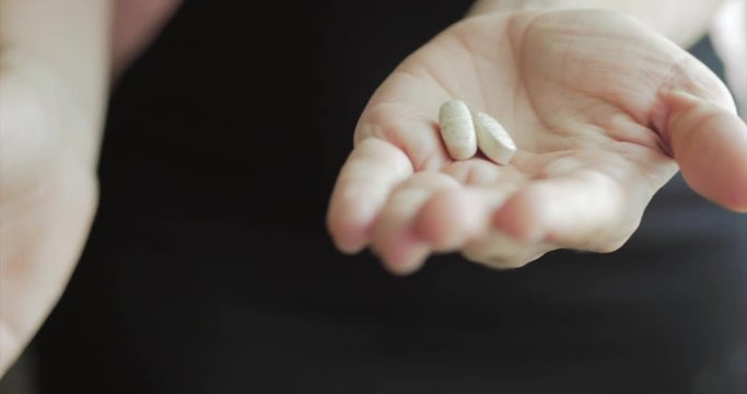 Close-up of Female Hands, Someone Pours a Bunch of Prescription Opiate Pills into the Hand. Concept of Health, Drugs, Contraception.