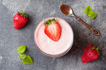 Homemade yogurt with fresh strawberries in glasses on a dark concrete background. Selective focus. Copy space.
