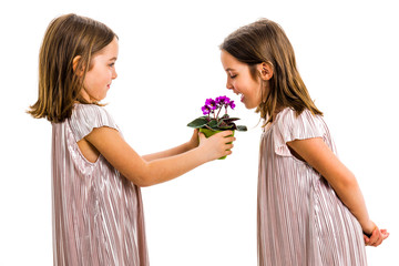 Identical twin girl is smelling flower - gift from sister.