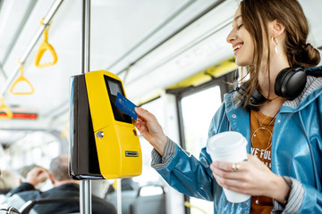 Woman paying conctactless with bank card for the public transport in the tram